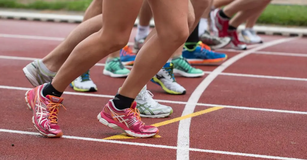 Close-up of marathon runners feet on wet asphalt in Porto, pace groups visible in background, autumn morning light, motion blur on legs, realistic sports photo