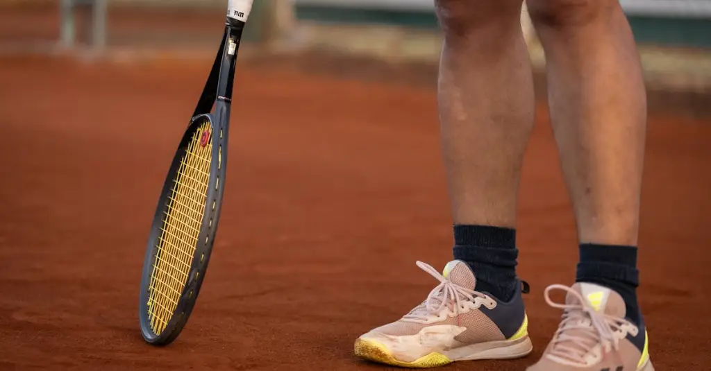 Professional tennis player sliding on red clay court at Roland Garros, intense rally, motion blur on feet, Paris tennis tournament atmosphere, photorealistic sports action shot