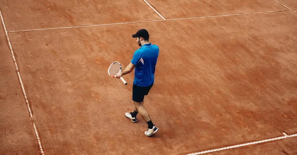 Athletic tennis player warming up on a clay court doing lateral agility drills, fitness training, spring afternoon light, photorealistic stock photo