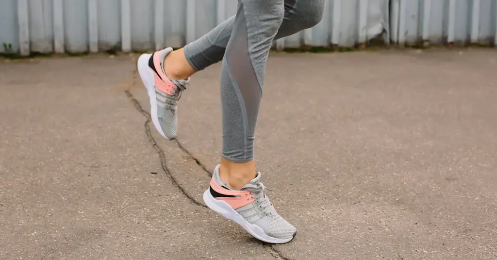 Close-up of a runner's legs and feet showing impact force on different surfaces: one foot on a synthetic athletics track and one foot on rocky trail terrain, biomechanics concept, studio-quality sports photography