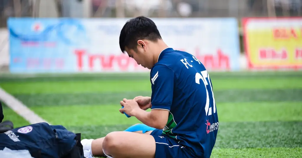 A football player checking a smartwatch with GPS data after a match, sweating, holding a water bottle, realistic sports photography, athletic recovery concept