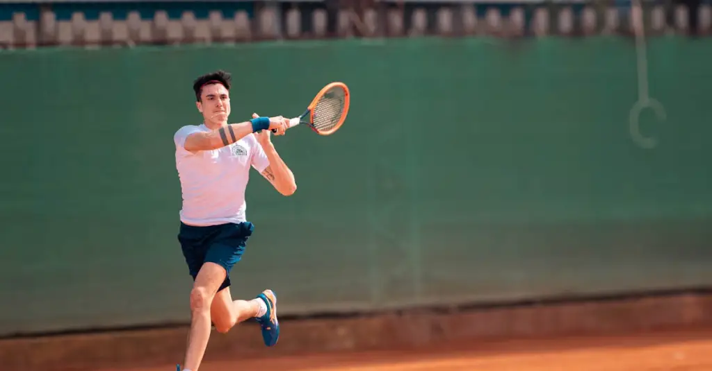 Professional male tennis player serving on a clay court during a Grand Slam tournament, motion blur on the racket, intense expression, stadium crowd in background, realistic sports photography